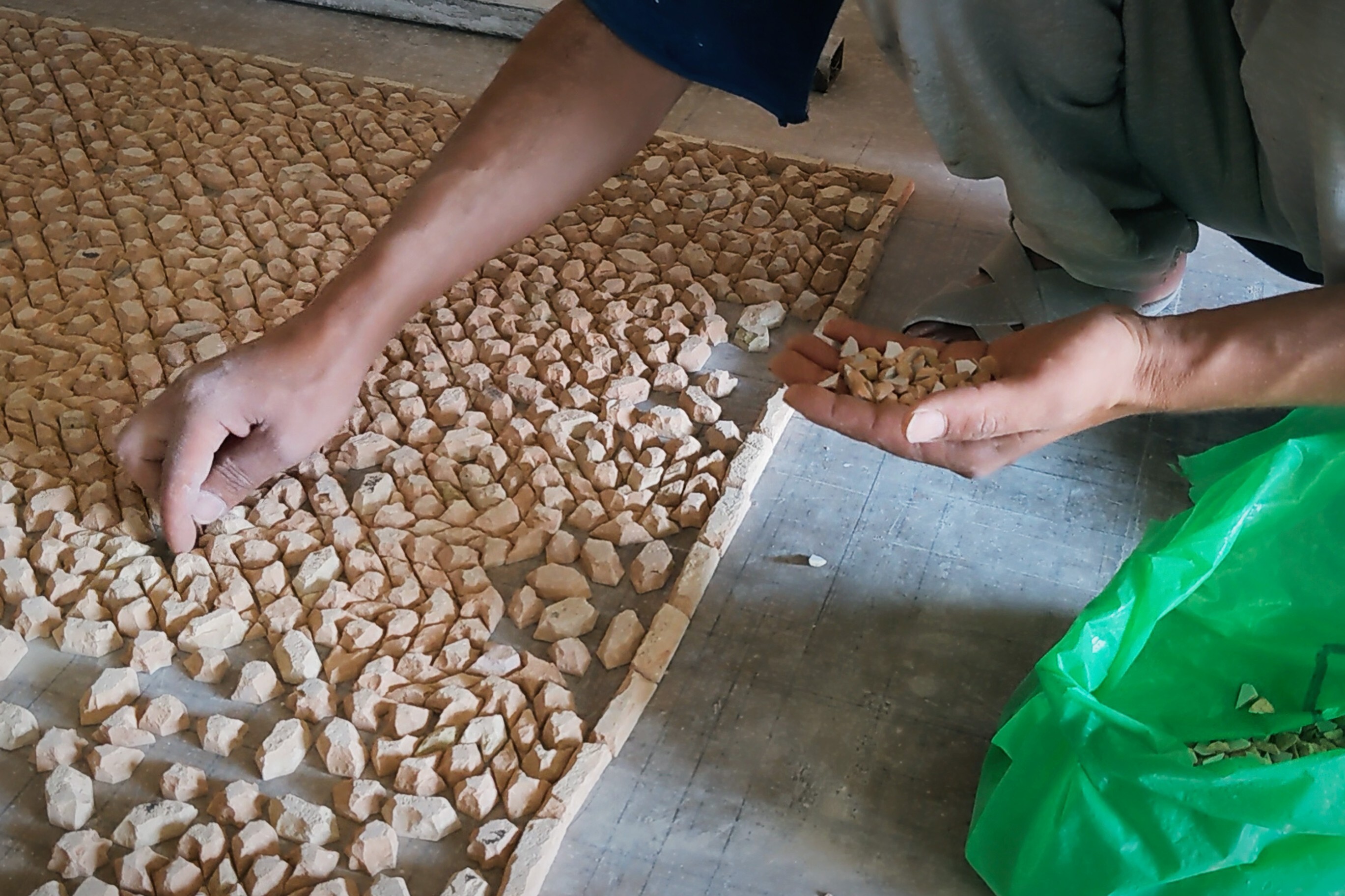 One moroccan craftsman kneeling to arrange Zellij tiles face down into a panel on the floor