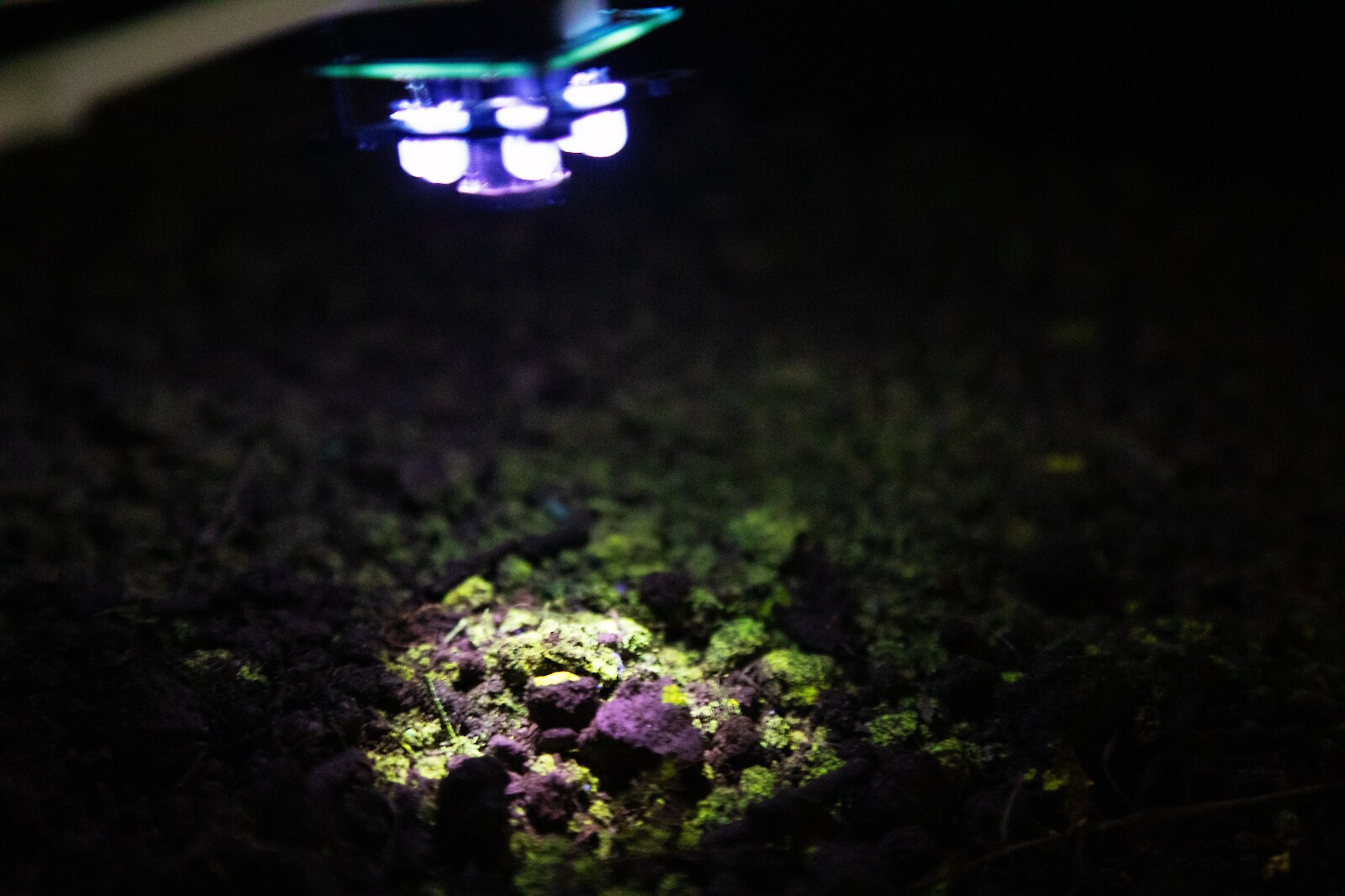 The repurposed drones scan the field at a close distance at night.