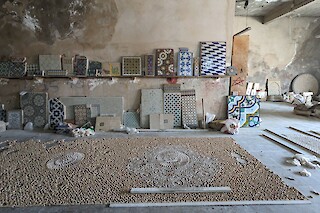 Incomplete Zellij panel on the floor and samples leaning against the wall of a craftsman’s workshop in Fes, Morocco