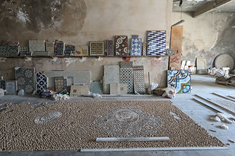 Incomplete Zellij panel on the floor and samples leaning against the wall of a craftsman’s workshop in Fes, Morocco
