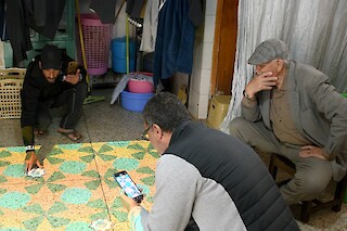 Three moroccan craftsmen kneeling to interact with markers on the floor.